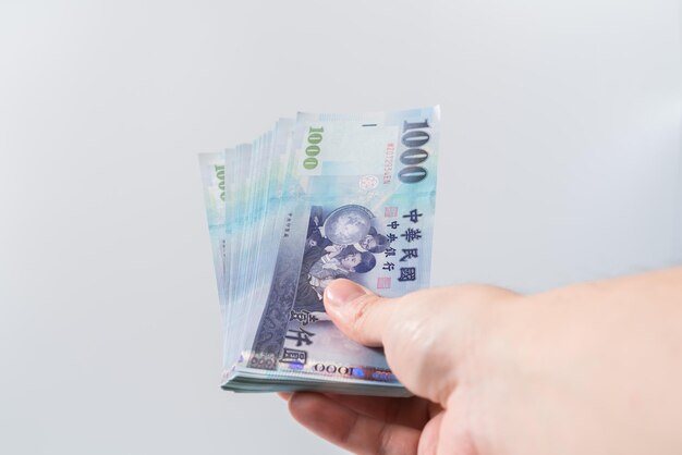 A hand holding a 1000 New Taiwan Dollar bill.