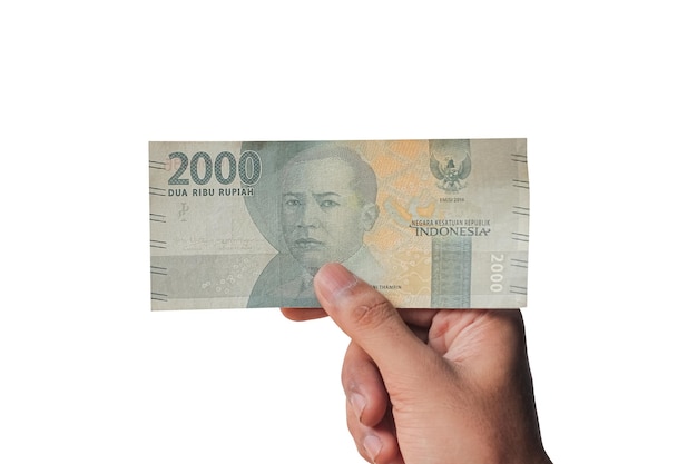 Photo hand holding 2000 rupiah isolated on white background. financial concept