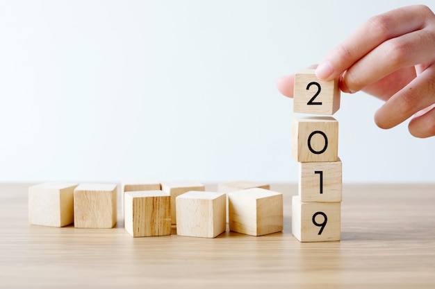 Рука 2019 счастливого нового года деревянные кубики на фоне стола