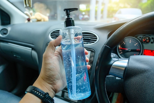 Photo hand holding alcohol gel inside car