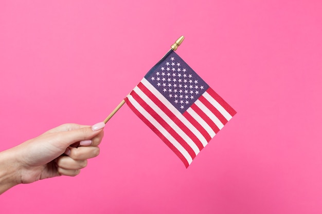 Hand holding american flag on pink