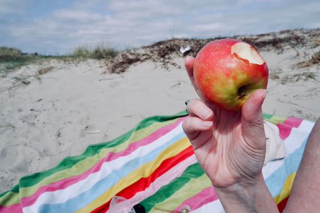 Foto la mano che tiene una mela sulla spiaggia