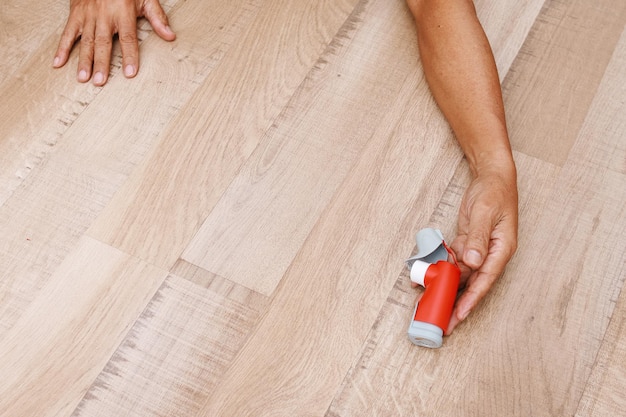 Hand holding asthma inhaler on wooden floor for relief asthma attacks