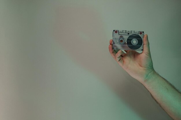 Photo hand holding audio cassette tape in the color light beautiful minimal in neon light minimalism ret