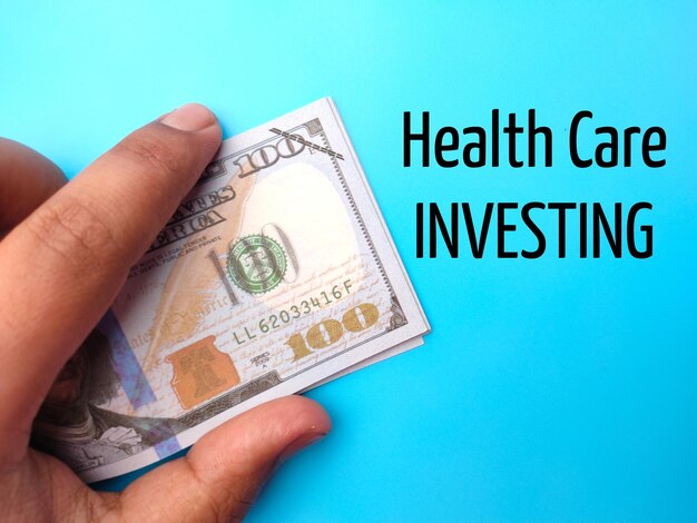 Рука держит банкноты с текстом health care investing на синем фоне