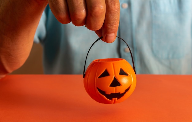 Hand holding basket of halloween pumpkin candies. Copy space. Selective focus.