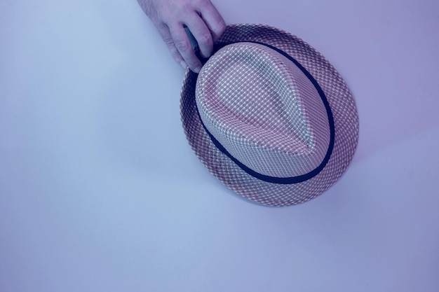 Hand holding Beautiful straw hat on a gray background