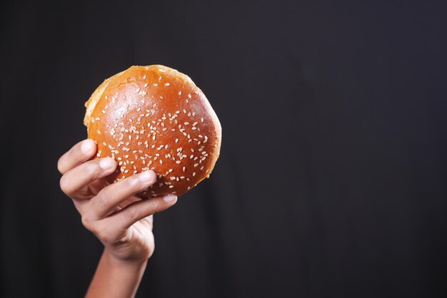 Hand holding beef burger isolated on black