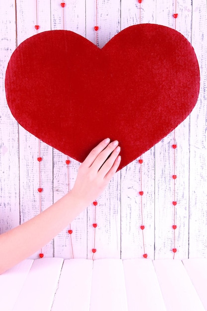 Hand holding big red heart on wooden background