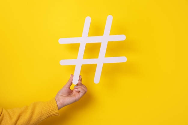 Hand holding big white hash sign, hashtag symbol of internet trends and popular blogs, recommendation to follow social media content.