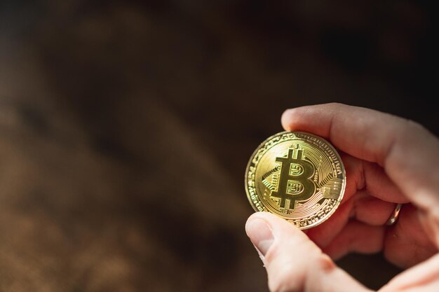 Hand holding a bitcoin cash coin in dark background with copy space.