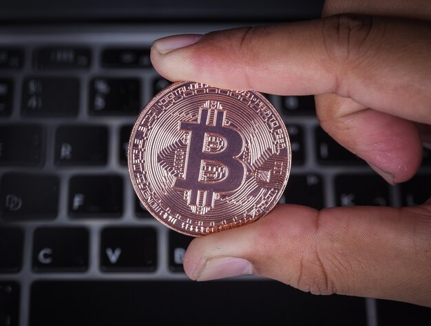 hand holding bitcoin with laptop computer 