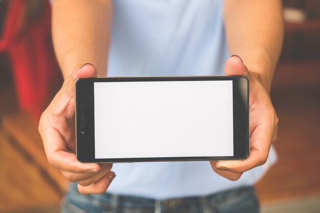 Hand holding black mobile smart phone with blank white screen at outdoor.