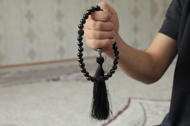 A hand holding a black tassel with the word buddha on it.