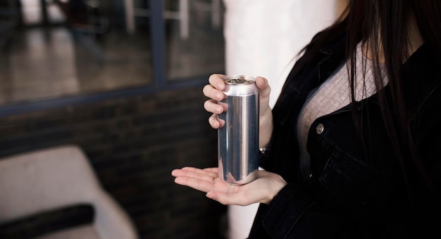 A hand holding a blank aluminium can template mockup with copy space