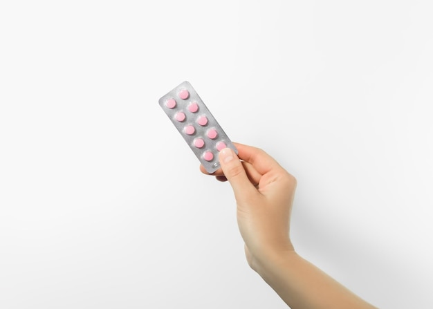 Photo hand holding blister with pink pills on white background