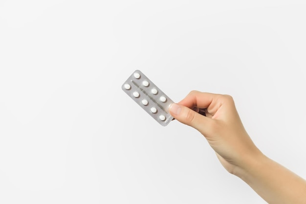 Photo hand holding a blister with white pills on a white background