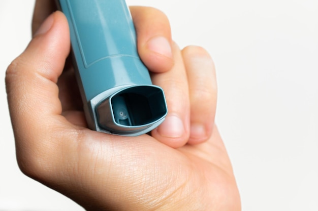 Hand holding a blue asthma inhaler.