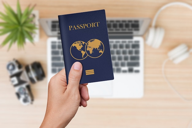 Hand holding blue passport with travel stuffs wall