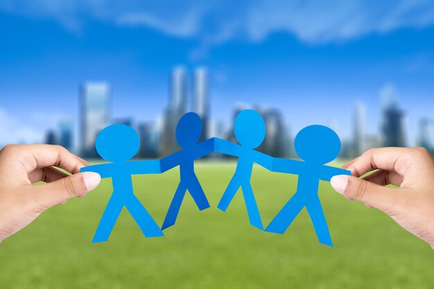 Photo hand holding blue people paper holding hands with cityscapes background. world population day concept