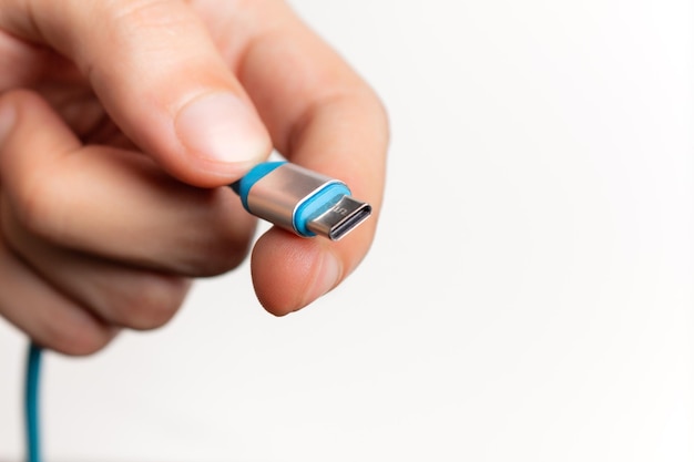 Hand holding a blue USB C cable on white background.