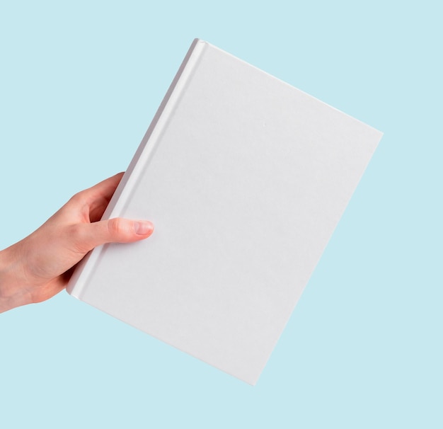 Modello di libro con mano su sfondo blu modello di copertina bianca concetto di lettura dell'istruzione letteraria
