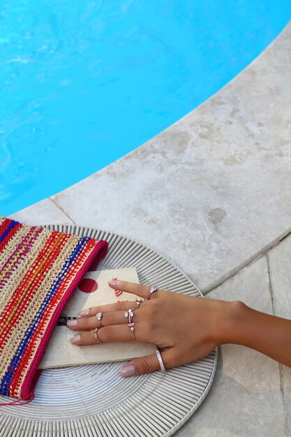 hand holding a book with a flower on the beach beautiful woman reading a book by the pool closeup Blank book