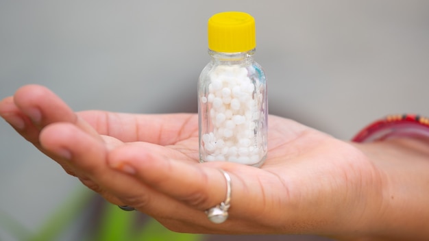 Hand Holding a Bottle of Homeopathic Medicine