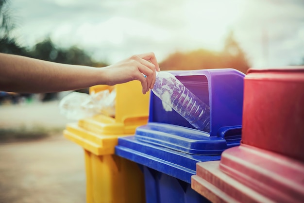 Hand holding bottle plastic garbage into trash in park