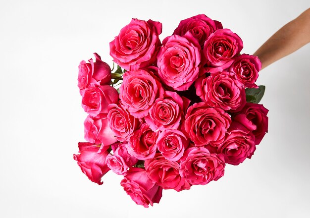 Hand holding a bouquet of pink roses on white background with copy space.