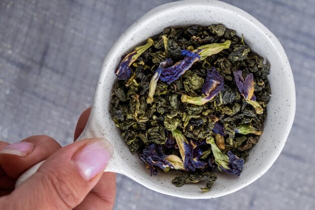 Hand holding a bowl of dry flower tea