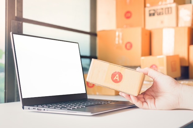 Hand holding a box and Laptop on the table neur.