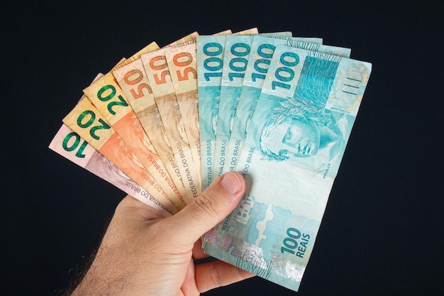 Hand holding Brazilian money banknotes Brazilian finance concept