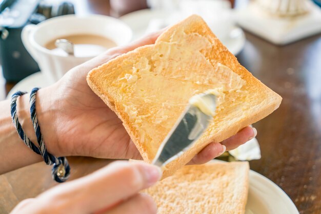 朝食用に作るパンとバターを手に持つ手