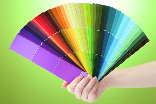 Hand holding bright palette of colors on green background