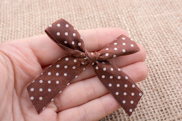 Hand holding brown color ribbon in hand
