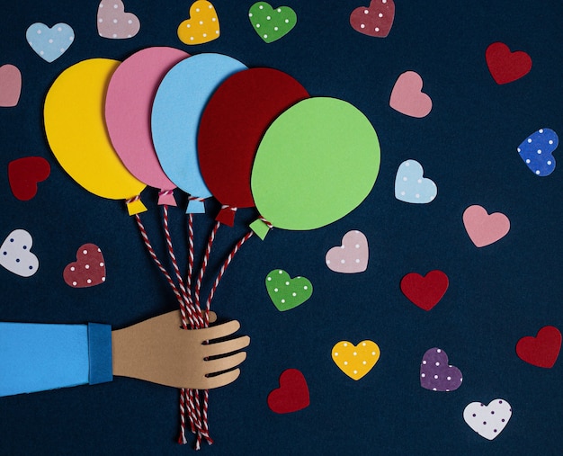 Hand holding a bunch of colorful paper balloons