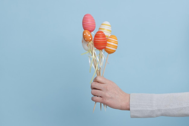 A hand holding a bunch of easter eggs on sticks