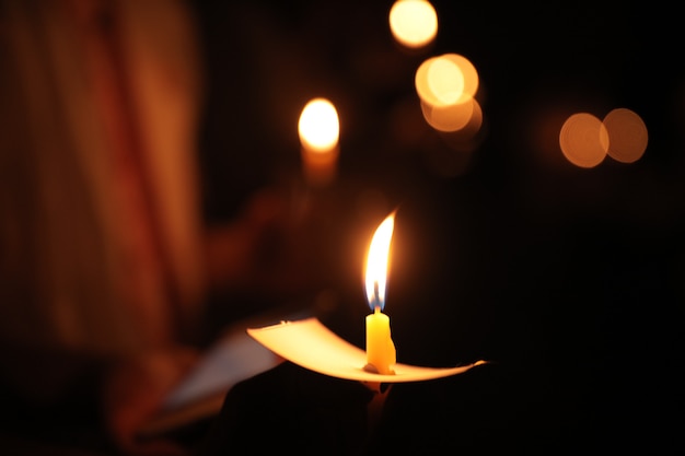 Hand holding a candle at night with bokeh on dark