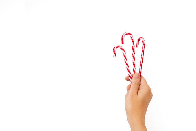 Hand holding candy canes on a white background