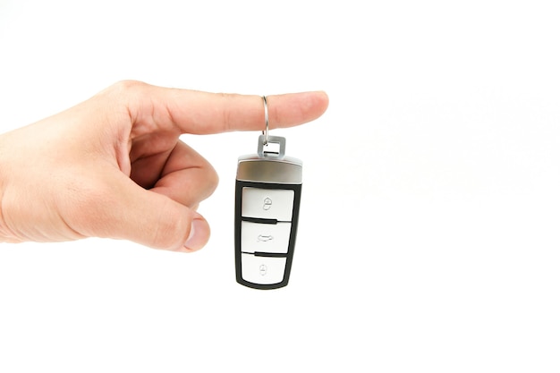 Hand holding a car key isolated on white