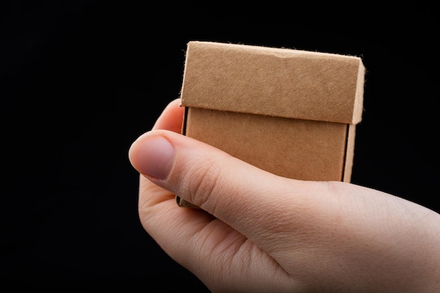 Hand holding cardboard box on a black background