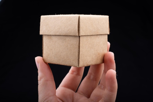 Hand holding cardboard box on a black background