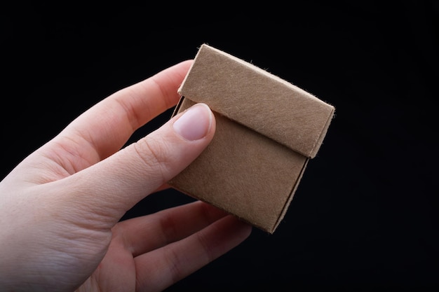 Hand holding cardboard box on a black background