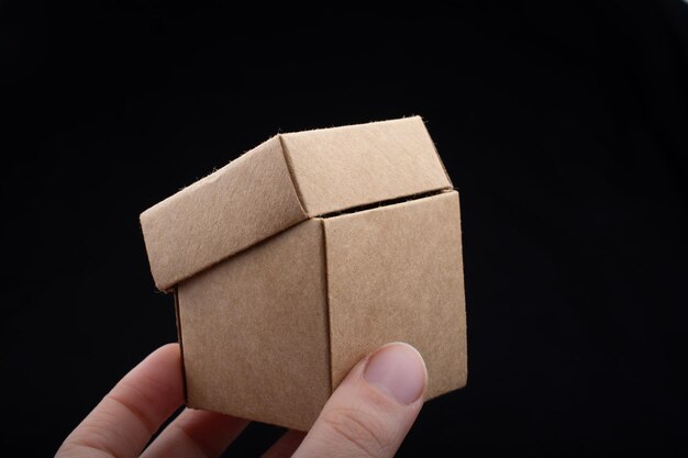 Hand holding cardboard box on a black background