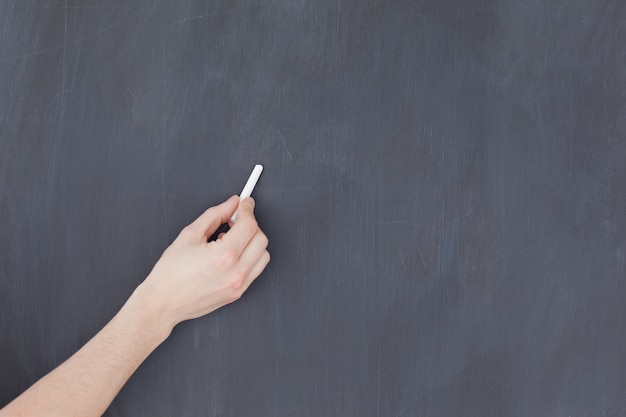 Photo hand holding a chalk and and ready to write on a blackboard