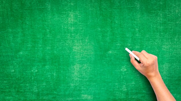 hand holding chalk writing on green chalk board good texture idea for text