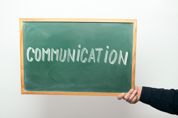 Hand holding a chalkboard with the word COMMUNICATION handwritten in chalk