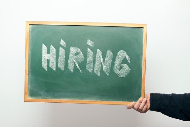 Photo hand holding a chalkboard with the word hiring handwritten in chalk