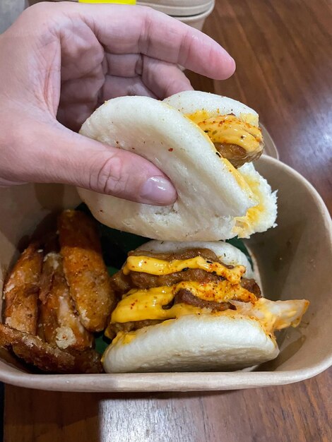 Hand holding chicken bao from the take out box